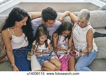 Stock Photography - Three generation family enjoying computer games on sofa. Fotosearch