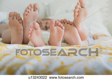 Three pairs of bare feet in a row, different sizes on a bed View Large Photo Image Stock Image - Three pairs of bare feet in a row, different sizes on a bed. Fotosearch