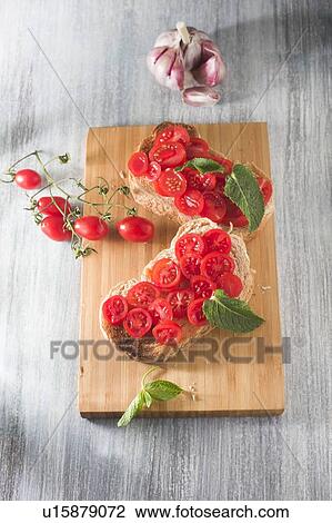 Stock Image - Toasted bread with tomatoes, garlic and herbs. Fotosearch