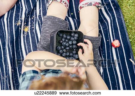 Toddler eating blueberries on picnic blanket View Large Photo Image Stock Photo - Toddler eating blueberries on picnic blanket. Fotosearch