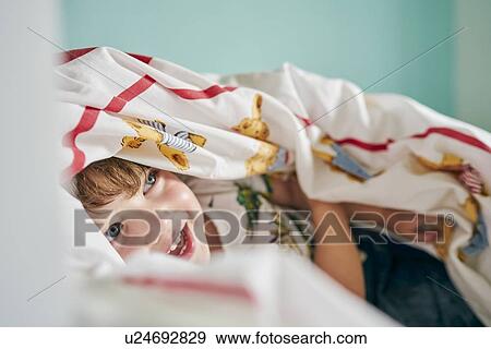 Toddler hiding under blanket in room View Large Photo Image Stock Photo - Toddler hiding under blanket in room. Fotosearch
