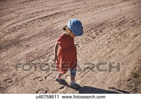 Toddler looking at shadow on dirt road View Large Photo Image Stock Image - Toddler looking at shadow on dirt road. Fotosearch