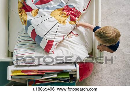 Stock Photograph - Toddler opening blanket on bed. Fotosearch