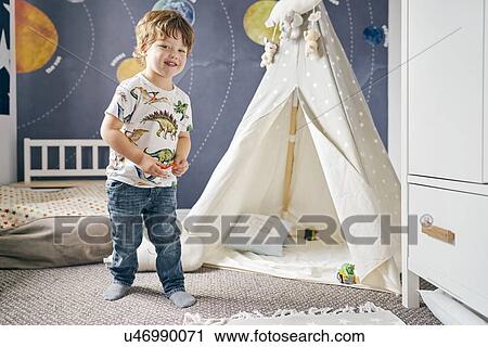Stock Image - Toddler playing in room, child's teepee, mural of solar system on wall. Fotosearch