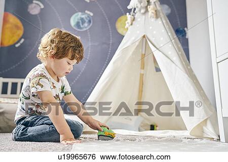 Stock Photograph - Toddler playing in room, child's teepee, mural of solar system on wall. Fotosearch