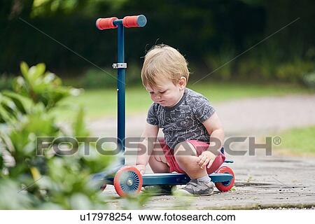 Toddler playing with push scooter in park View Large Photo Image Picture - Toddler playing with push scooter in park. Fotosearch