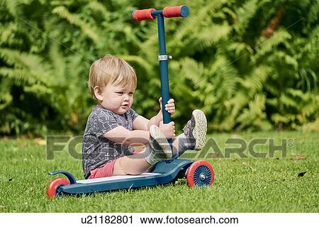 Toddler playing with push scooter in park View Large Photo Image Stock Image - Toddler playing with push scooter in park. Fotosearch