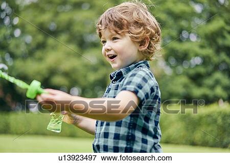 Toddler playing with soap bubbles in park View Large Photo Image Stock Photo - Toddler playing with soap bubbles in park. Fotosearch