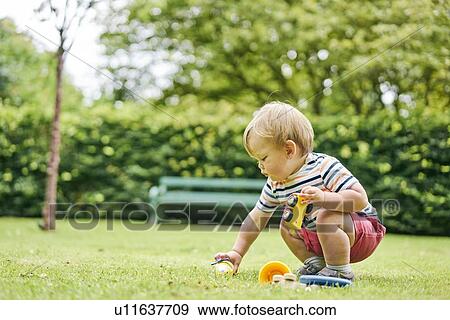 Stock Photo - Toddler playing with toy car in park. Fotosearch