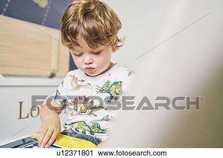 Toddler reading book in room View Large Photo Image Stock Image - Toddler reading book in room. Fotosearch