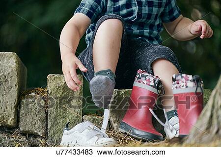 Toddler removing shoe beside tree View Large Photo Image Stock Image - Toddler removing shoe beside tree. Fotosearch