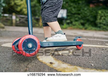 Picture - Toddler riding on push scooter in park. Fotosearch