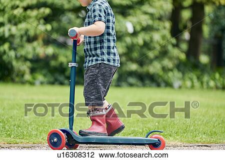 Toddler riding on push scooter in park View Large Photo Image Stock Image - Toddler riding on push scooter in park. Fotosearch