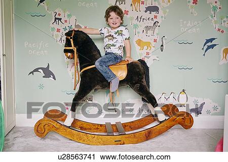 Toddler riding on rocking chair in room View Large Photo Image Stock Image - Toddler riding on rocking chair in room. Fotosearch