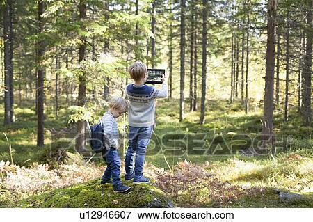 Stock Photo - Toddler with brother taking photograph of forest. Fotosearch