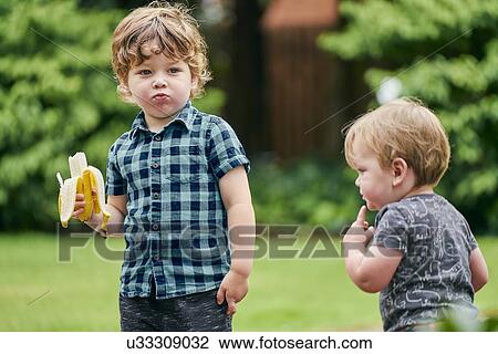 Toddlers exploring and eating banana in park View Large Photo Image Stock Image - Toddlers exploring and eating banana in park. Fotosearch