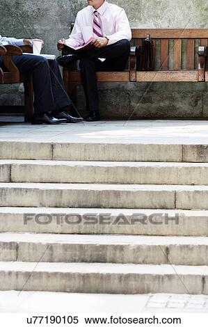 Two businessmen having meeting on park bench outside View Large Photo Image Stock Photography - Two businessmen having meeting on park bench outside. Fotosearch