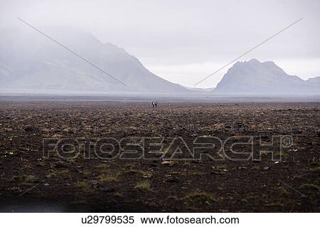 Stock Photography - Two people in middle of vast flat landscape, Landmannalaugar, Iceland. Fotosearch