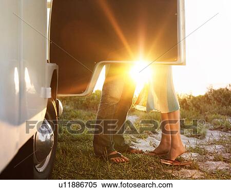 Two people standing behind car door with sun shining in background View Large Photo Image Stock Photography - Two people standing behind car door with sun shining in background. Fotosearch