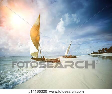 Two sail boats on a beach with sea and the sun View Large Photo Image Stock Image - Two sail boats on a beach with sea and the sun. Fotosearch