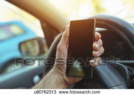 Stock Image - Using smartphone while driving. Fotosearch