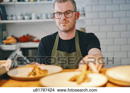 Picture - Waiter placing food on service counter in restaurant. Fotosearch