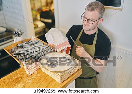 Stock Photography - Waiter wiping cutleries in restaurant. Fotosearch