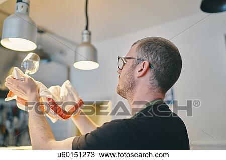 Stock Image - Waiter wiping wine glass in restaurant. Fotosearch