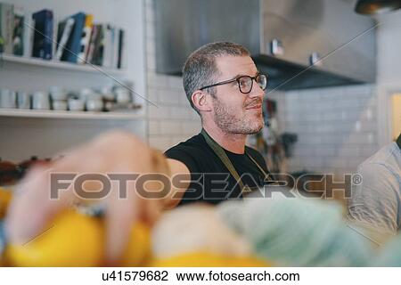 Stock Image - Waiter working behind service counter in restaurant. Fotosearch