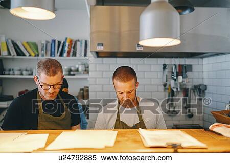 Waiters working behind service counter in restaurant View Large Photo Image Stock Photography - Waiters working behind service counter in restaurant. Fotosearch