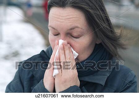 Stock Image - Woman blowing her nose. Fotosearch