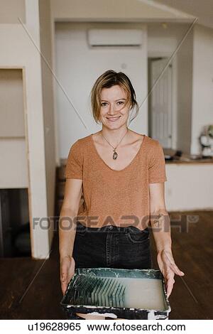 Stock Photography - Woman carrying tray of paint in new home. Fotosearch