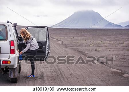 Woman changing shoes by vehicle door on dirt track, Landmannalaugar, Iceland View Large Photo Image Stock Photo - Woman changing shoes by vehicle door on dirt track, Landmannalaugar, Iceland. Fotosearch