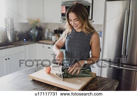 Stock Image - Woman cutting fresh vegetables on cutting board. Fotosearch