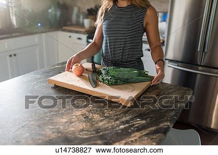 Stock Photo - Woman cutting fresh vegetables on cutting board. Fotosearch