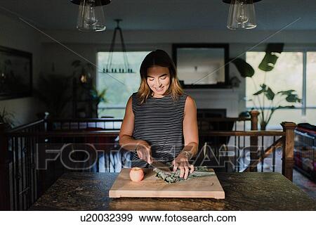 Stock Photo - Woman cutting fresh vegetables on cutting board. Fotosearch