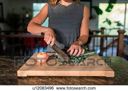 Stock Photograph - Woman cutting fresh vegetables on cutting board. Fotosearch