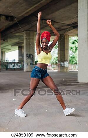Stock Photo - Woman dancing under bridge in city. Fotosearch