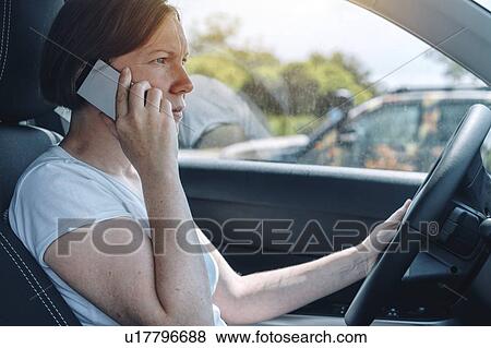Stock Photo - Woman driving car and using phone. Fotosearch