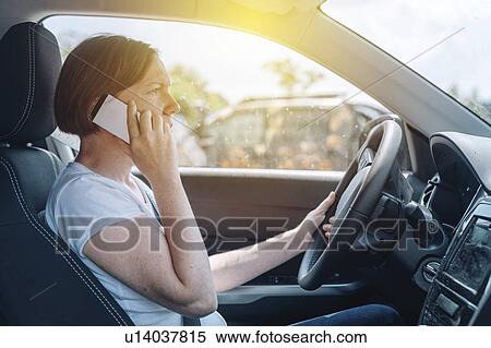 Stock Photography - Woman driving car and using phone. Fotosearch