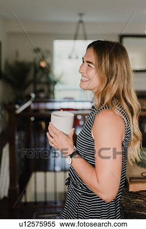 Stock Photography - Woman enjoying cup of hot beverage at home. Fotosearch
