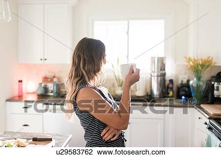 Woman enjoying cup of hot beverage in kitchen View Large Photo Image Stock Image - Woman enjoying cup of hot beverage in kitchen. Fotosearch