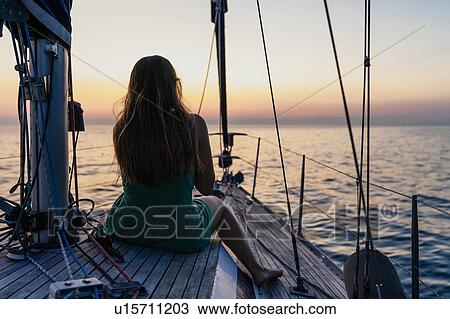 Stock Image - Woman enjoying sunset on sailboat, Italy. Fotosearch