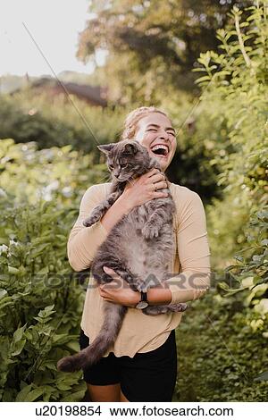 Picture - Woman gardener carrying cat in garden. Fotosearch