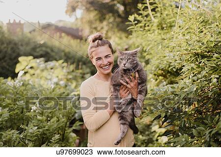 Woman gardener carrying cat in garden View Large Photo Image Stock Image - Woman gardener carrying cat in garden. Fotosearch