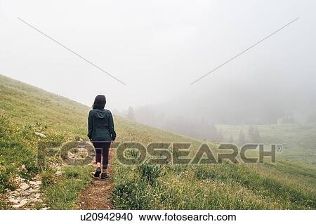 Woman hiking on hilltop, thick fog in background View Large Photo Image Stock Image - Woman hiking on hilltop, thick fog in background. Fotosearch