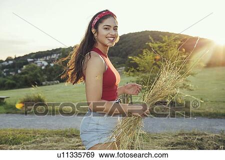 Stock Photo - Woman holding hay in sunshine, Wilhelminenberg, Vienna, Austria. Fotosearch