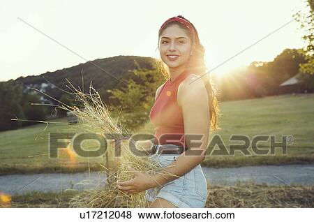 Stock Photo - Woman holding hay in sunshine, Wilhelminenberg, Vienna, Austria. Fotosearch