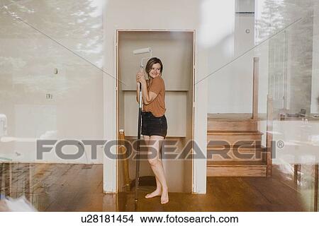 Picture - Woman holding paint roller stick in new home. Fotosearch