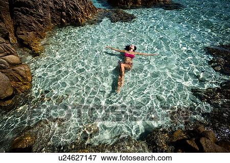 Stock Photo - Woman in bikini enjoying clear sea water in lagoon, La Maddalena island, Sardegna, Italy. Fotosearch